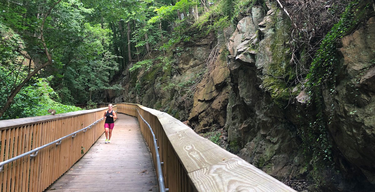 Woman running on a bridge in the woods.