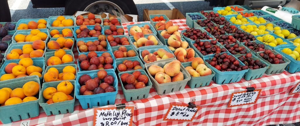 Various stone fruit, like plums, peaches and cherries, in quart containers on a table at the Northwest Chamber of Commerce Farmers Market.